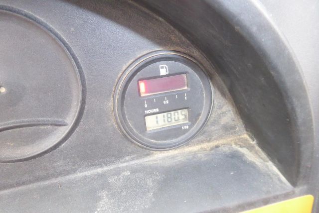 Gauge cluster shows fuel gauge with red indicator at near full, and a digital hour meter reading 11805 hours. Surrounding panel is dark plastic with dusty surface.