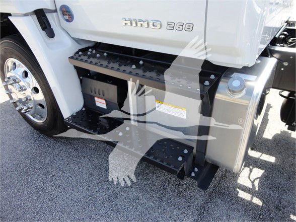 Front lower side of a white 2022 Hino 268A truck showing the HINO 268 badge, steps, and fuel/engine compartments with metal riveted steps.