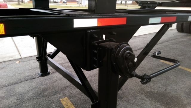 Trailer kingpin and support frame of a 2009 Great Dane dump trailer with round bottom, showing black metal chassis and hydraulic landing gear.