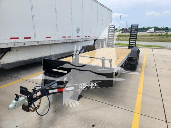 Behnke flatbed trailer in a parking lot showing front hitch and gooseneck, Behnke logo on frame, stake pockets, and loading ramps.