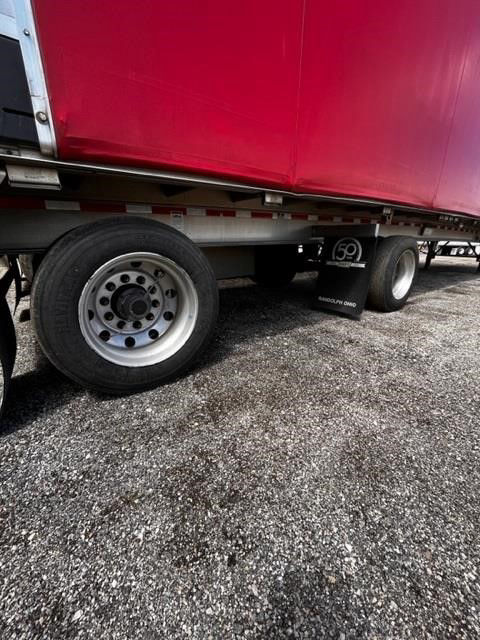 Trailer with red curtain side and rolling tarp system; dual rear axles with aluminum wheels; mudflap shows '50' emblem.