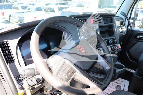 Cab interior of a Kenworth T880 showing steering wheel, dashboard, and center console with controls and display.