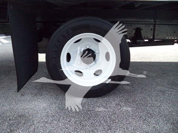 Isuzu NRR wheel and tire visible under truck with white steel rim; partial undercarriage and frame visible.