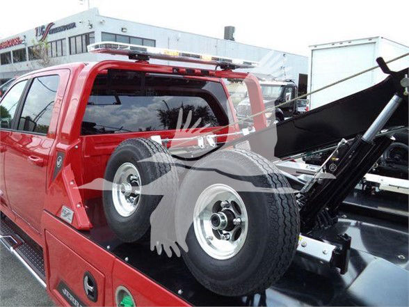 Ram 5500 tow truck flatbed with spare tires mounted in the bed.