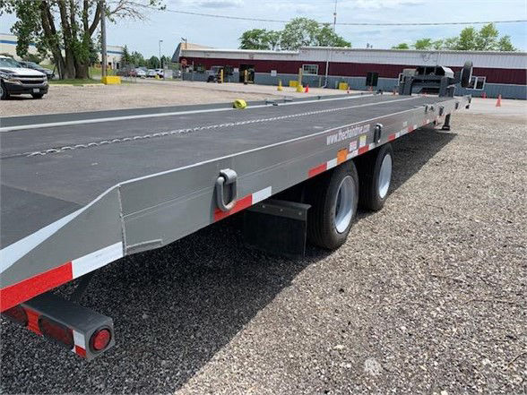 Trailer side view showing tandem axle drop deck container trailer with grey metallic finish, chain strap, and red/white reflective tape.