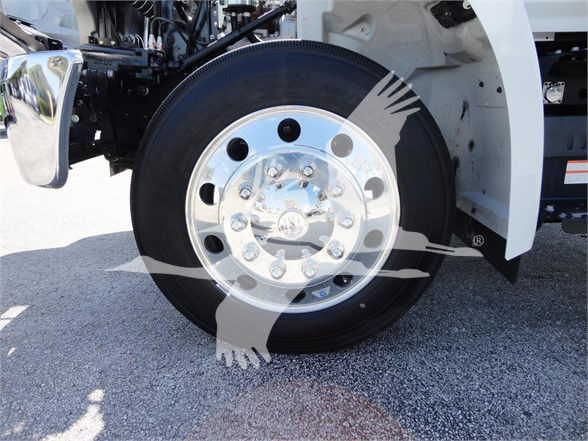 Front wheel and fender of a 2022 Hino 268A tow truck with chrome wheel, black tire, white body.