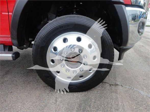 Ram 5500 hooklift truck front wheel and tire showing steel wheel and hub, partial fender and mud flap.