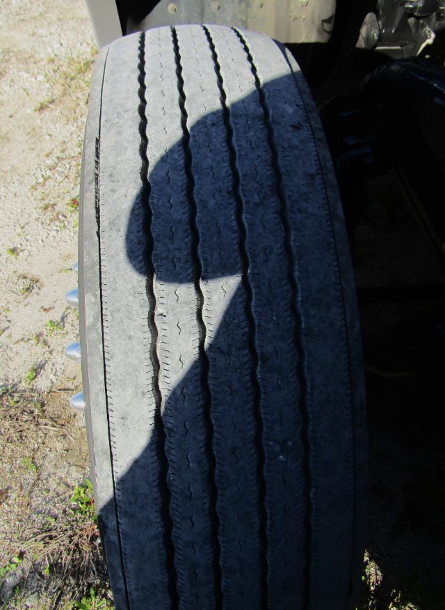 Rear tire on a Kenworth T680 cab and chassis showing tread wear and sidewall markings.