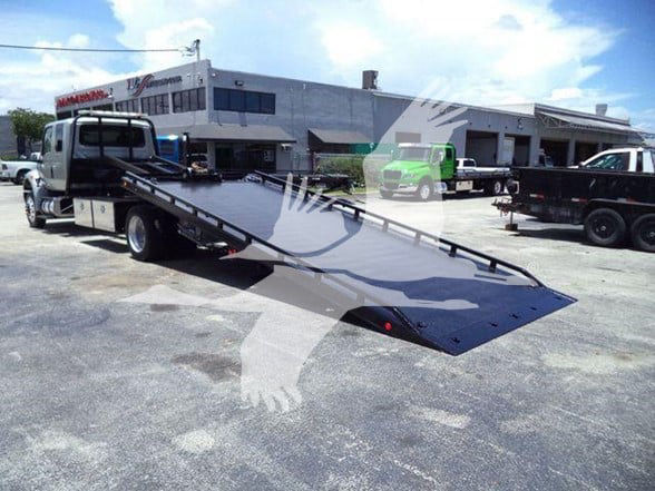 Tow truck with a long black flatbed ramp, International MV category Tow truck visible in background, stock number T50307.