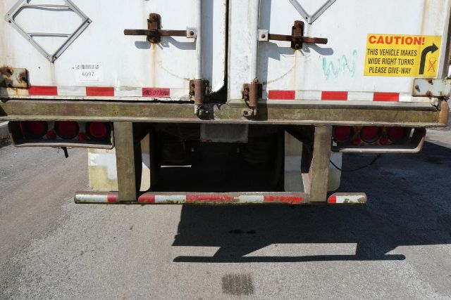 Rear view of a Fruehauf trailer with dual rear doors, rear bumper, and CAUTION sticker on right door.