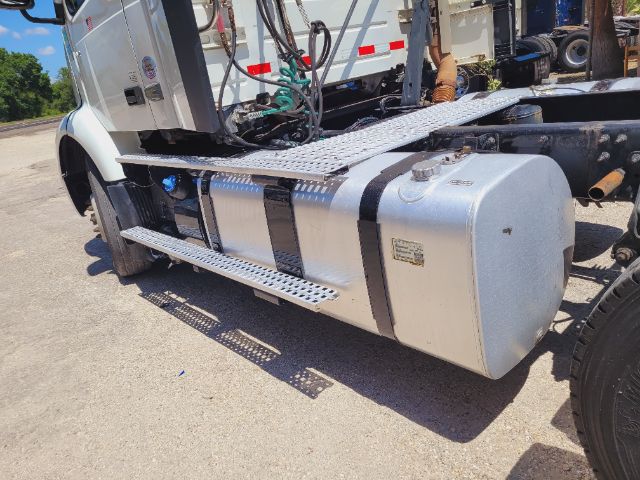 Side view of a Volvo VNR daycab showing aluminum cylindrical fuel tank, metal steps, and chassis frame.