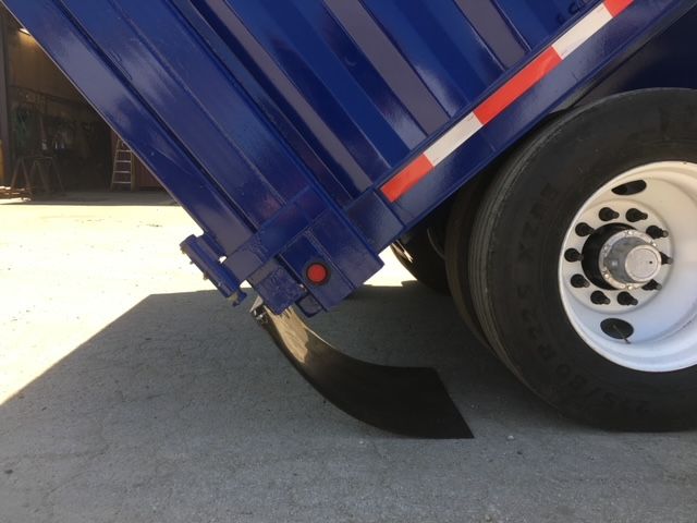 Rear-left side of a blue 2006 square dump trailer with its bed raised, showing a black mud flap and white wheel.