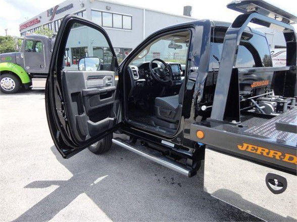 Ram 5500 SLT truck with driver door open showing interior, step bar, and tow truck bed attachment.
