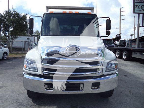 Front view of a white 2016 Hino 268A dump truck showing chrome grille, headlights, and front bumper.