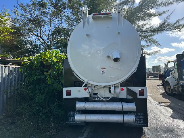 Rear view of a vacuum truck with a large circular tank, rear bumper, and two cylindrical exhaust-like outlets under the tank.