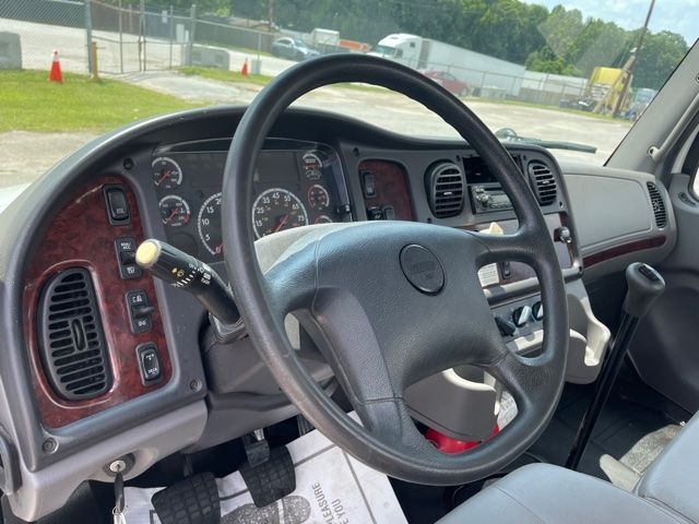 Cab interior of a 2013 Freightliner M2 truck showing steering wheel, dashboard gauges, and control panels.