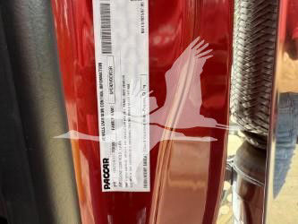 Label on red Kenworth T880 showing packaging barcode and PAOCAR/ PACCAR tag; vertical sticker with barcodes and text near door frame.