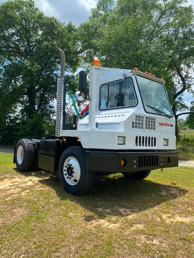 Olive-green Ottawa YT30 yard truck cab front-left view with vertical exhaust stack and orange beacon lights.