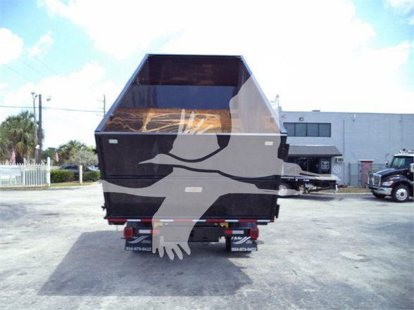 Back view of a 2023 International CV refuse truck with a large black dump bed. No visible text other than reflections.