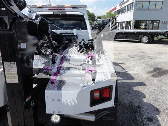 Ram 5500 truck bed with tilted cab, diamond plate metal steps, control levers, and rear lights in tow truck setup.