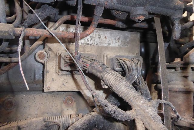 Truck engine bay showing a Cummins EFISB 5.9L engine area with wiring harnesses and corrosion on metal blocks.