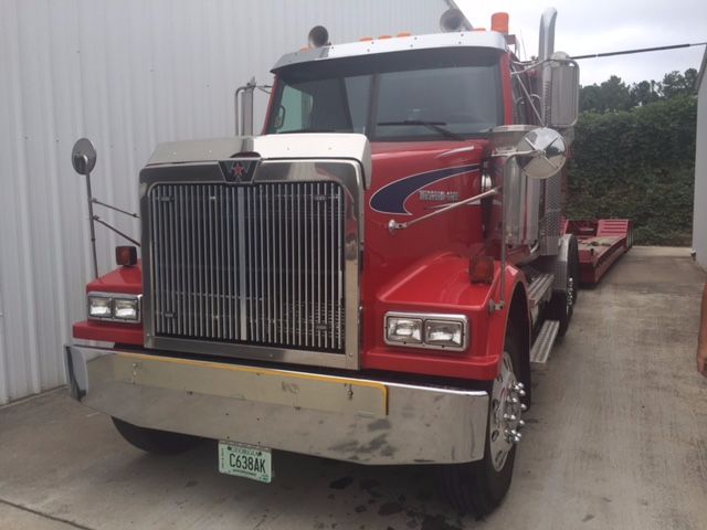 Truck front view showing 2007 Western Star 4900fa conventional sleeper; chrome grille, large bumper, rectangular headlights, red cab with chrome accents and a green license plate.