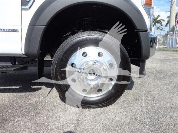 Ford F-550 front wheel and fender of a white dump truck with wheel and tire visible.