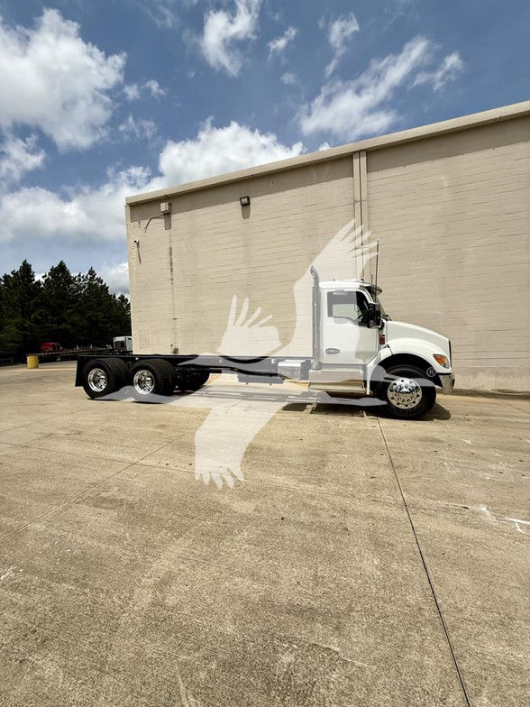 Kenworth T480 cab and chassis truck in a parking lot showing side view with long wheelbase and dual rear axles.
