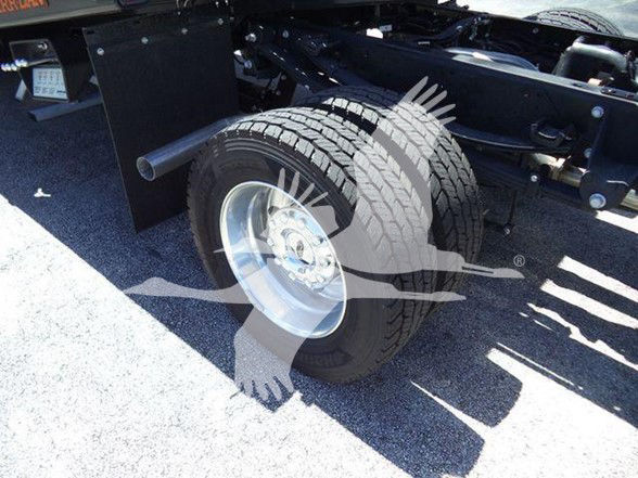 Front wheel and chassis of a 2024 Ford F600 XLT truck showing single rear wheel and suspension, with visible tire treads and wheel rim.