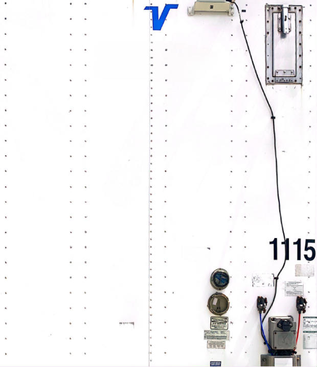 Trailer door area showing Vanguard logo and utility trailer components including fuel and electrical connections and serial/sticker labels.