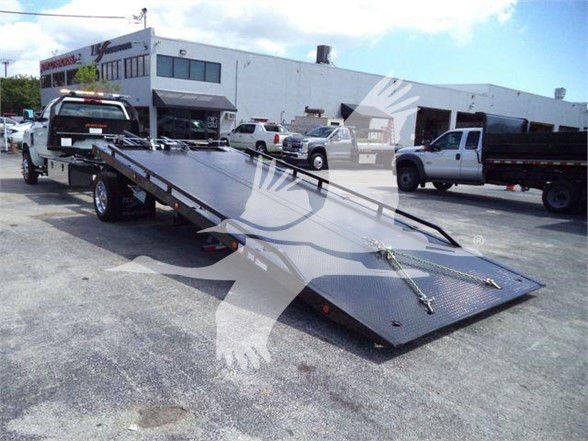 Truck tow rig with a low-profile flatbed trailer in a dealership lot, International CV context.
