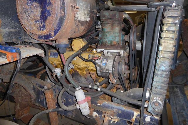 Ford 8000 engine bay showing yellow engine block with belts and hoses, radiator in front, air compressor and various components connected with wiring.