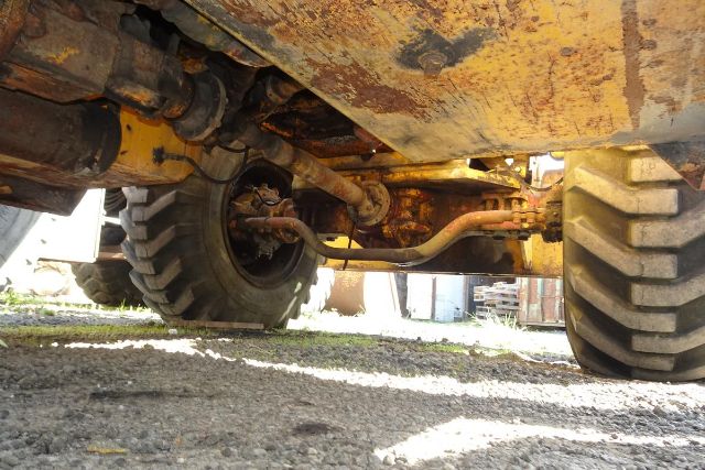 Grove RT58 crane undercarriage showing wheel axles, hydraulic hoses, and rust-colored frame with yellow paint.