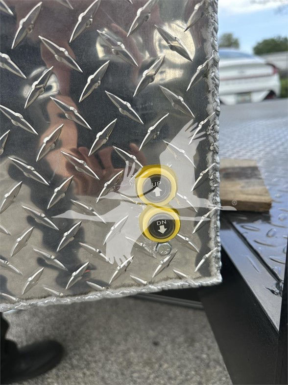 Diamond plate trailer corner with dual yellow-rimmed push buttons labeled UP and DN.