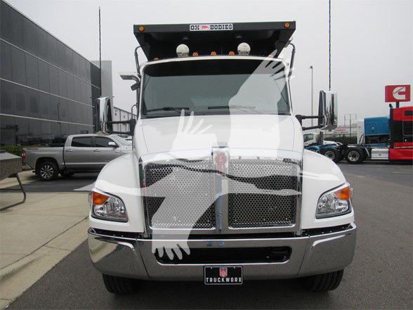 Front view of white Kenworth T480 dump truck with shiny chrome bumper and grille, cab mirrors, and light bars on the roof.