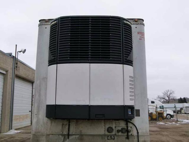 Reefer trailer front view with large black grille and silver panels, warning label on right vertical pillar, and control box at lower middle.