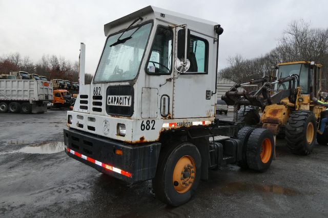 Capacity TJ5000 yard truck showing cab with number 682 and Capacity logo, with a second heavy equipment vehicle in the background.