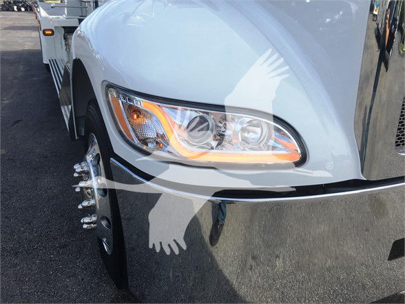Peterbilt 337 front wheel area showing headlight and chrome bumper, white cab with reflection, front hub with lug nuts.