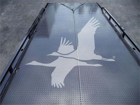 Tow truck bed with diamond plate surface and a white flying bird graphic.