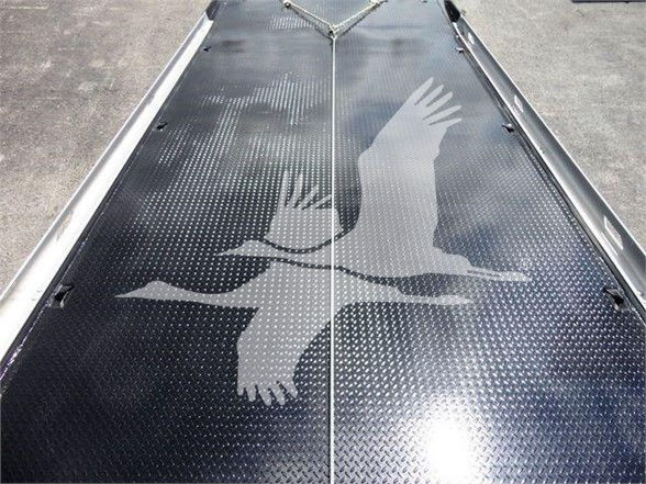 Truck bed or ramp with diamond plate texture and a graphic of two birds in flight.