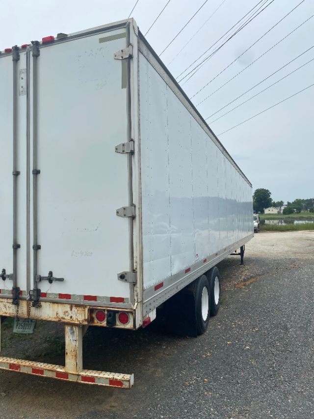 Trailer end and side of a white 2015 Wabash Duraplate trailer with dual rear doors and tandem axles.