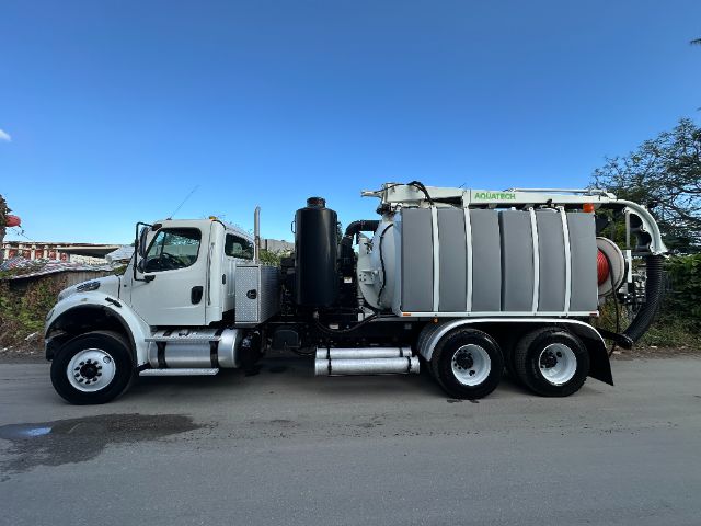 Vacuum truck chassis with large tank and rear hose reel, 2014 Freightliner M2, white cab, multiple axles, blue sky.