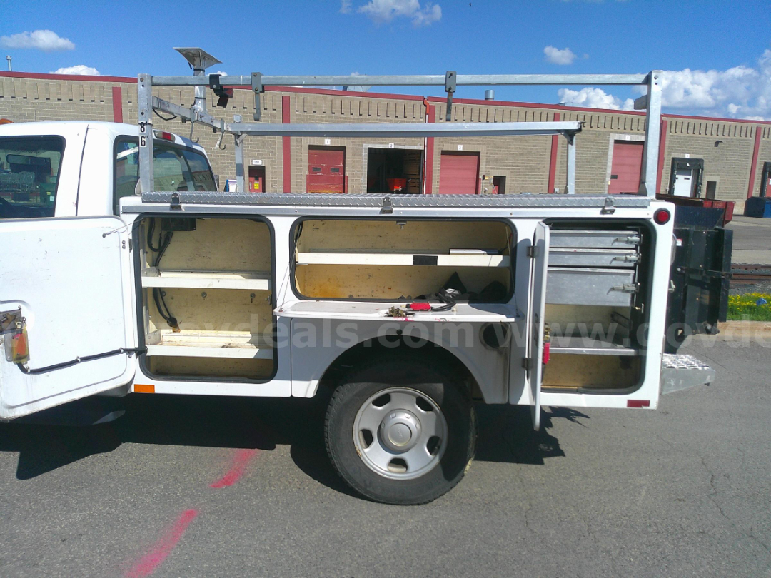 Service/Utility truck side body with open compartments and shelves, toolbox drawer unit, metal ladder rack on top, rear open door showing storage, single wheel visible.