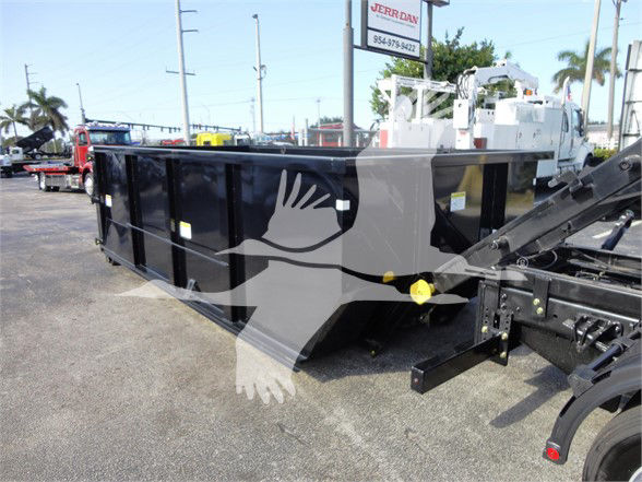 Truck dump bed attached to 2023 Chevrolet Silverado 5500HD with black exterior and hydraulic mechanism, showroom lot in background.