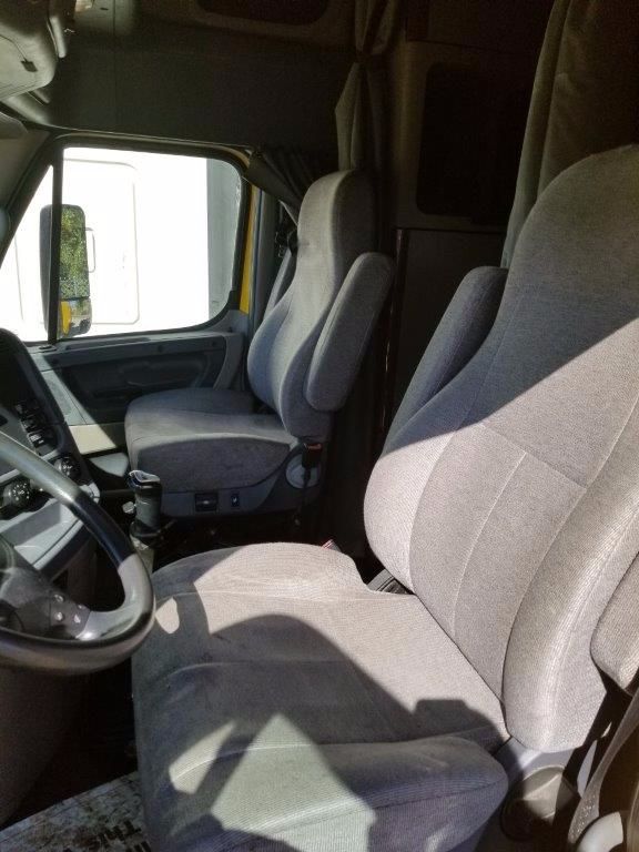 Cab interior of a 2012 Freightliner Cascadia truck showing driver and passenger seats, steering wheel, and center console.