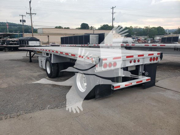 Flatbed trailer with white and red reflective tape, dual rear axles, and heavy-duty chassis. Visible text includes no explicit model numbers on the rear; the trailer is a 2015 Reitnouer Maxmiser as listed.
