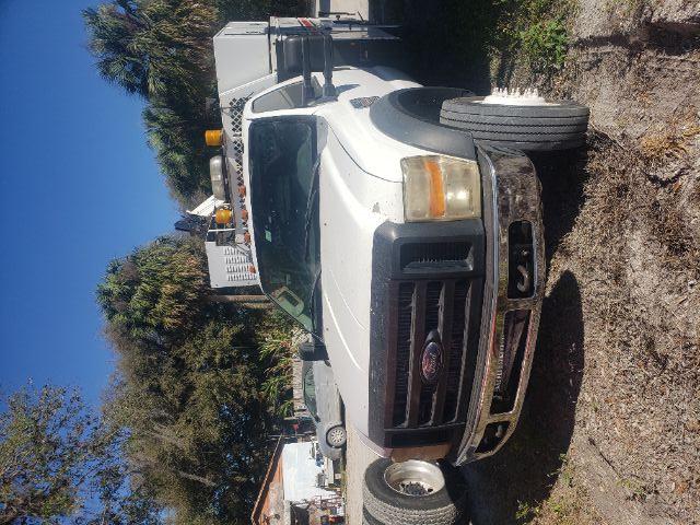2008 Ford F-550 utility truck front view with company equipment on bed and two yellow beacon lights on cab roof.
