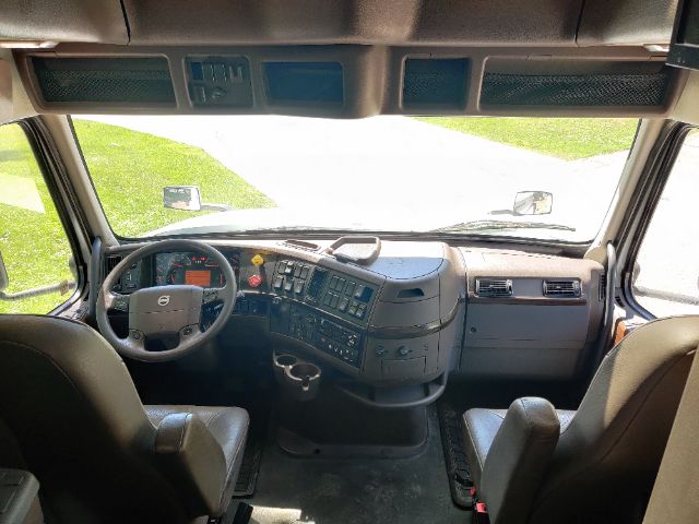 Volvo truck cab interior showing steering wheel, dashboard with control panels, and two front seats.