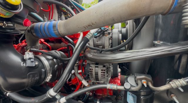 Freightliner 114SD engine bay showing hoses, wiring, alternator, and engine components.