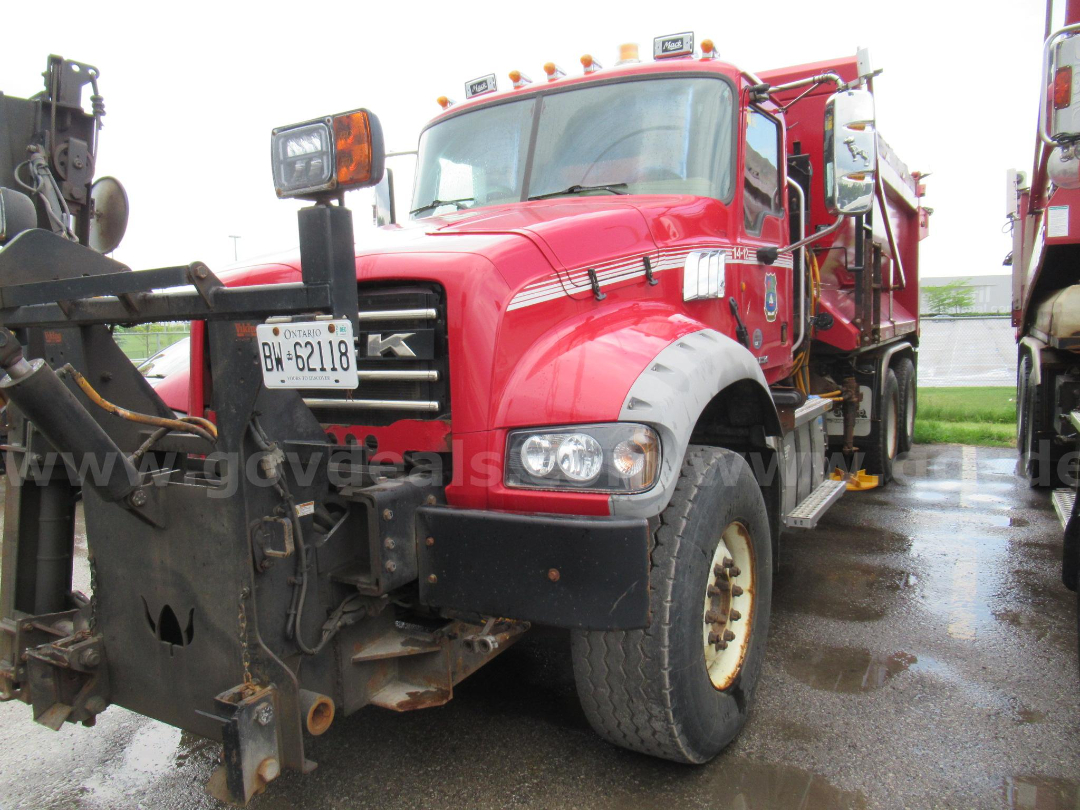 Red 2014 Mack GU713 plow truck showing front grille, headlights, and attached plow equipment.